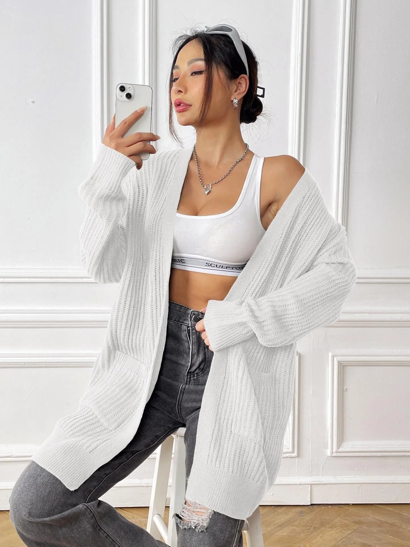A loose-fitting, mid-length acrylic cardigan sweater in a solid colour, shown in a street hipster style.