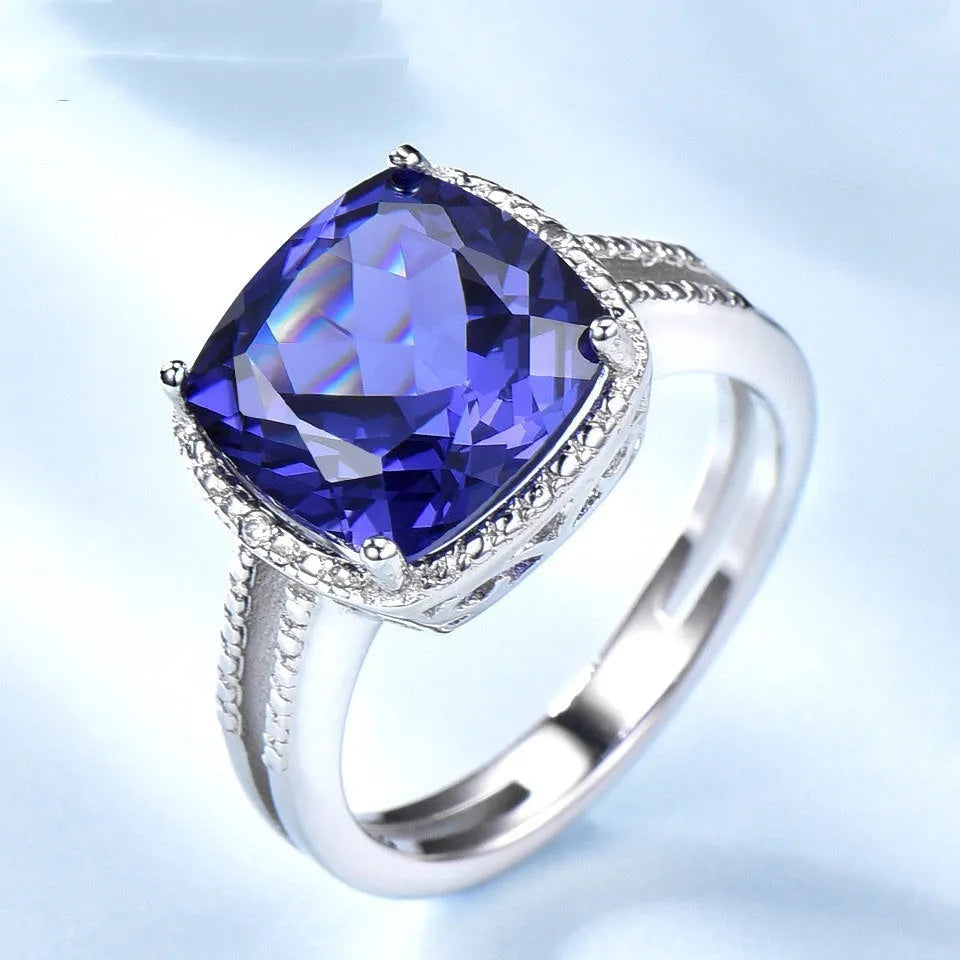 Women's sterling silver ring with a blue tanzanite gemstone on a model's hand.