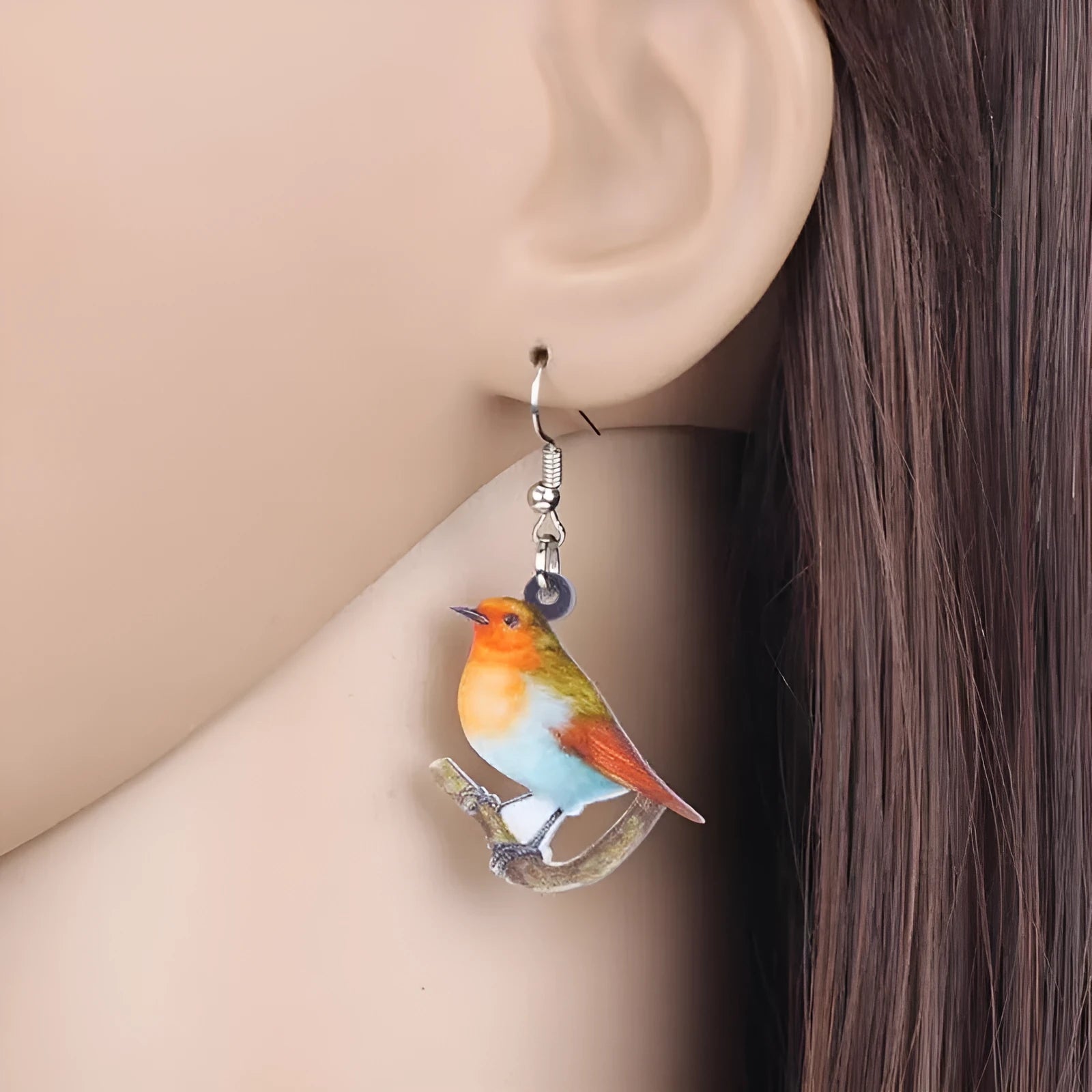 A pair of blue titmouse bird pendant earrings made from clear acrylic with geometric shapes and snake chain links.