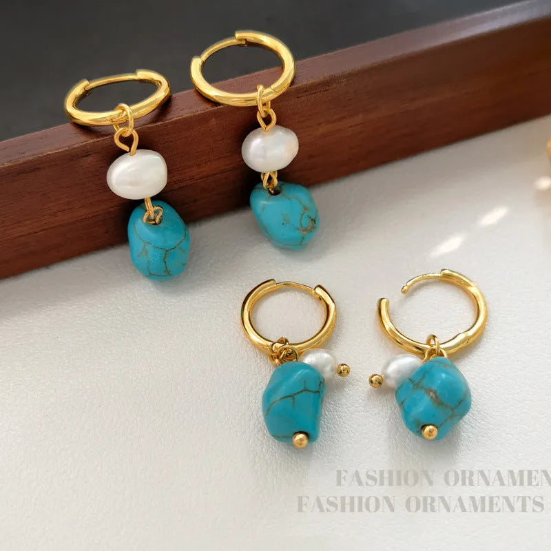 A pair of geometric turquoise and cultured pearl ear clips on a copper setting.