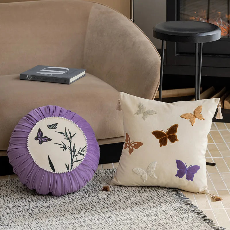 Square beige cushion with detailed purple and black butterfly embroidery in a Chinese floral pattern.