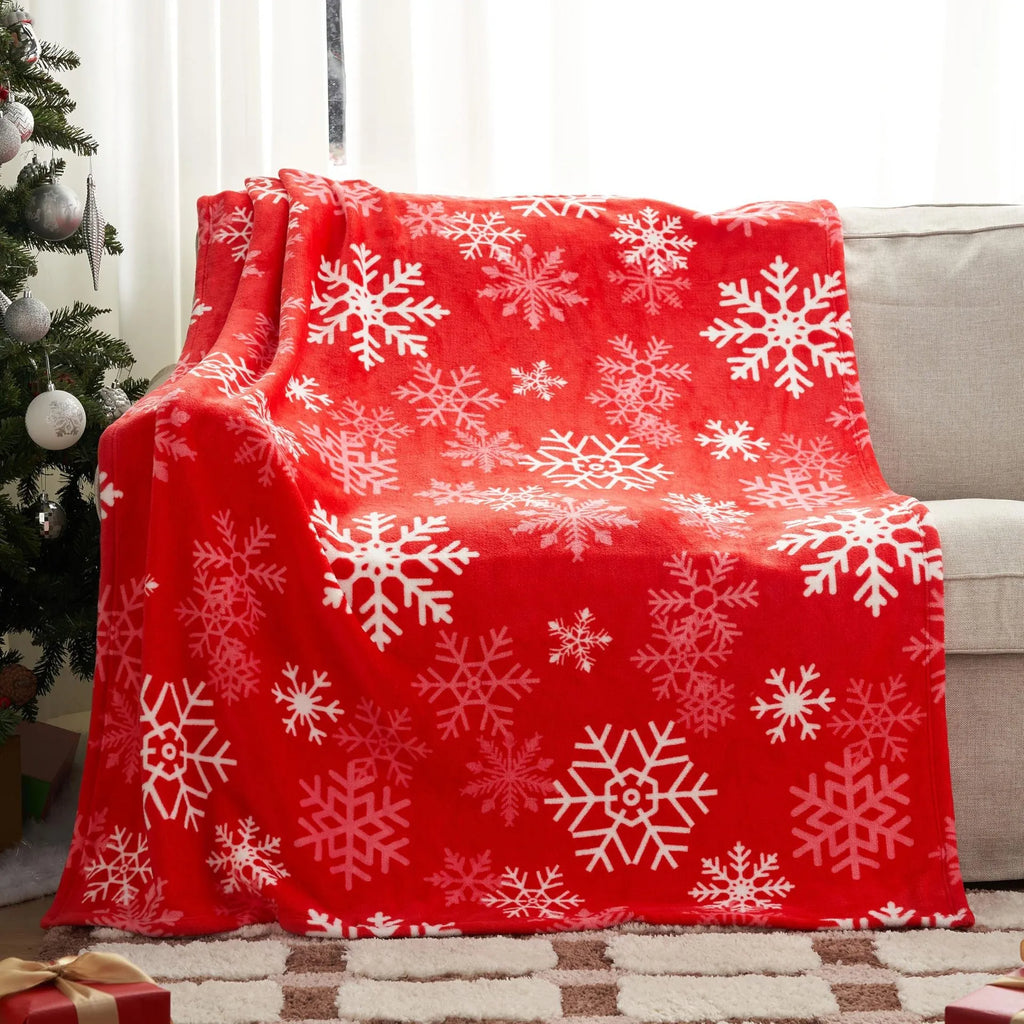Soft red flannel Christmas blanket draped over a sofa, showing its plush texture and generous size.