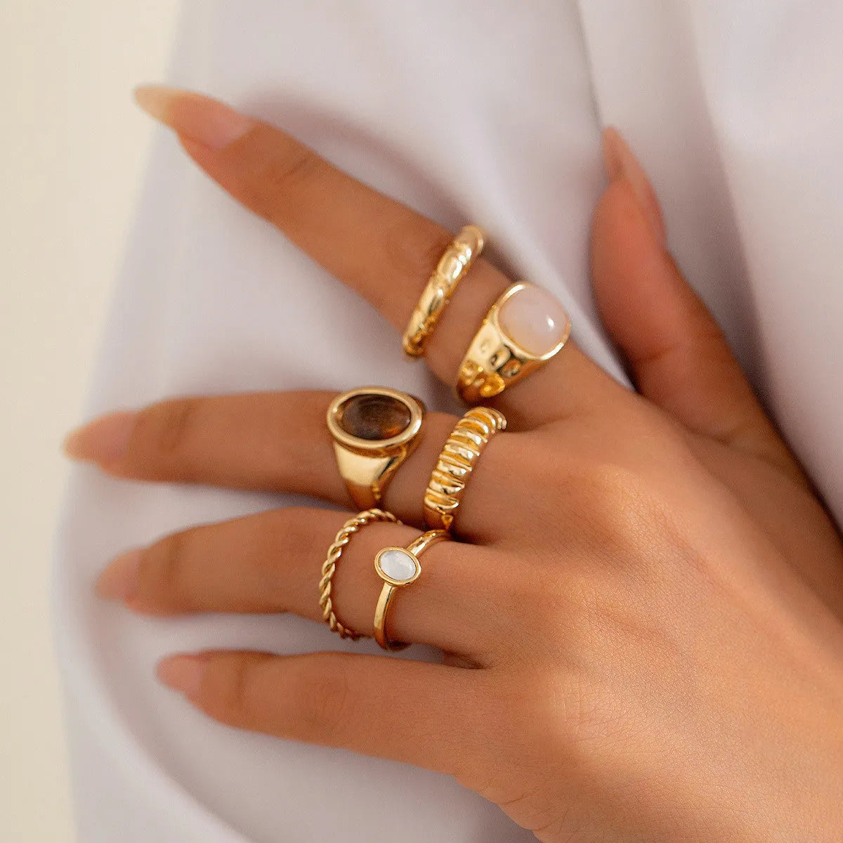 Set of six light gold alloy rings with irregular geometric shapes and rounded elements