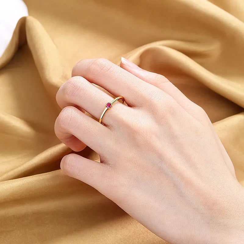 A simple single diamond ring with a fine circular copper band, shown in blue, green, red, and white colour variations.