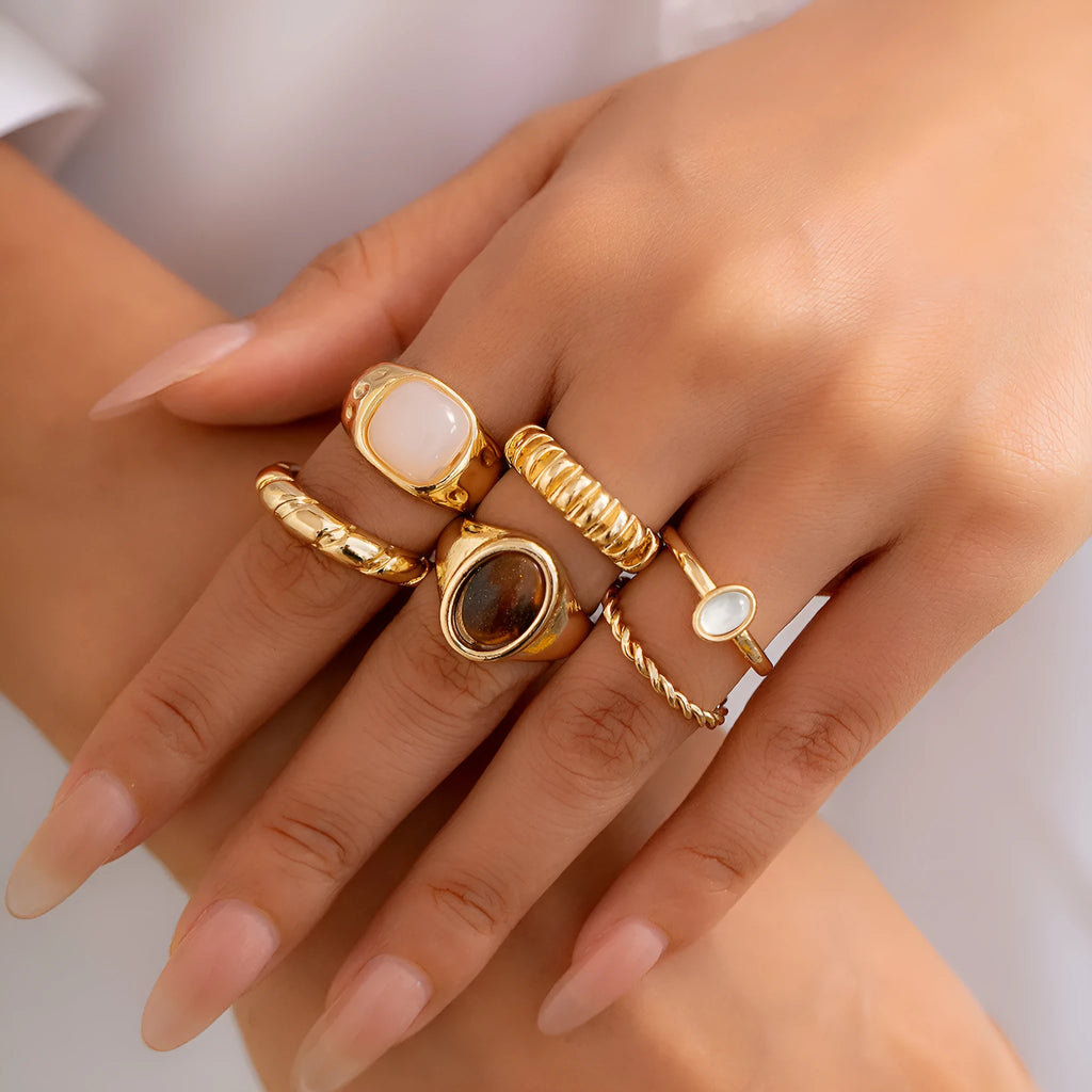Set of six light gold alloy rings with irregular geometric shapes and rounded elements