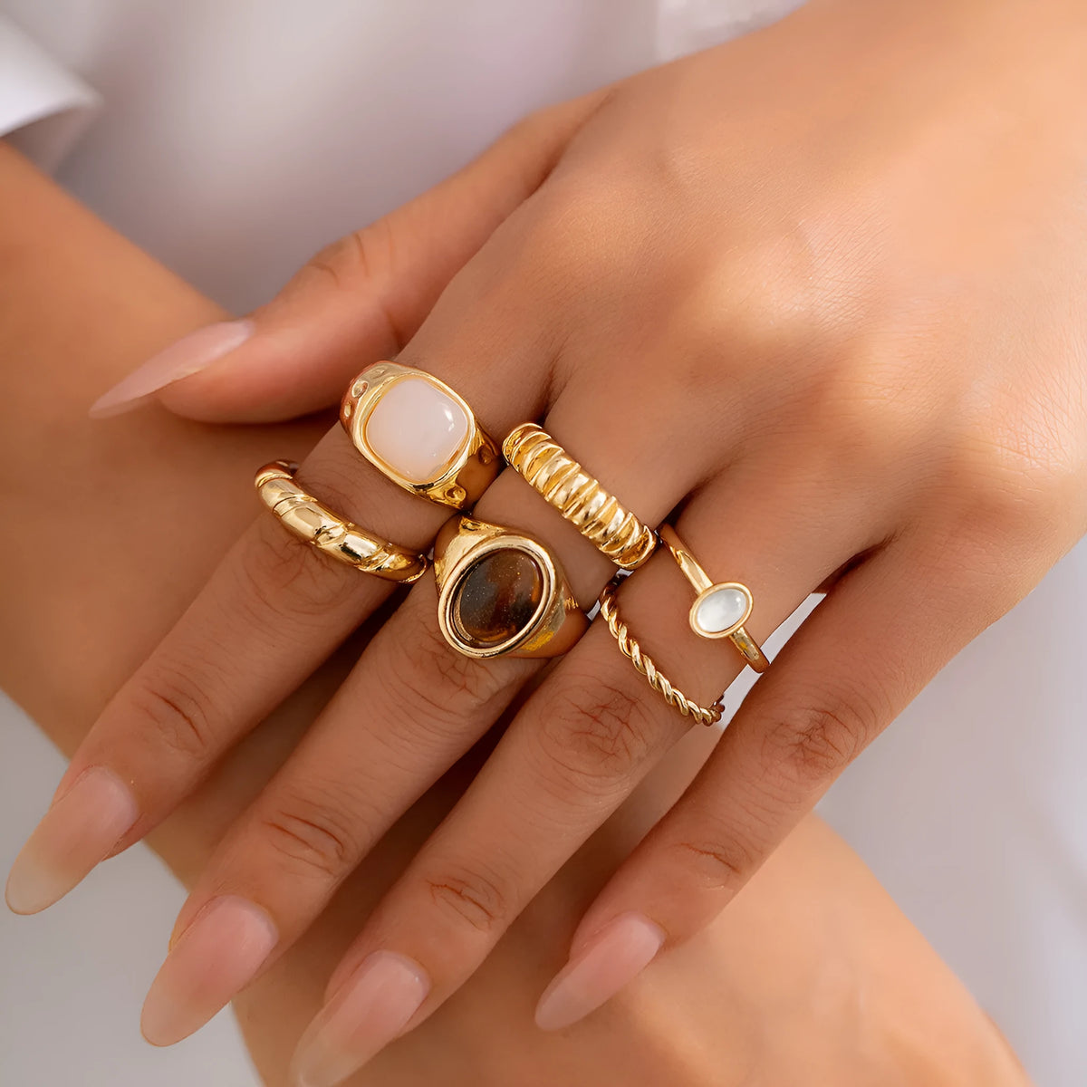 Set of six light gold alloy rings with irregular geometric shapes and rounded elements