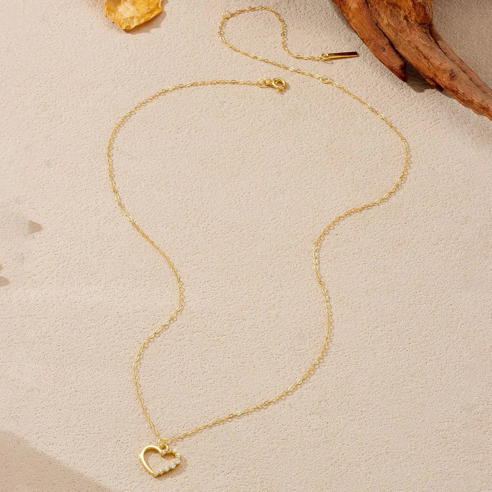 Close-up of a hollow heart-shaped sterling silver pendant on an oval chain, shown in both gold and white gold plated finishes.