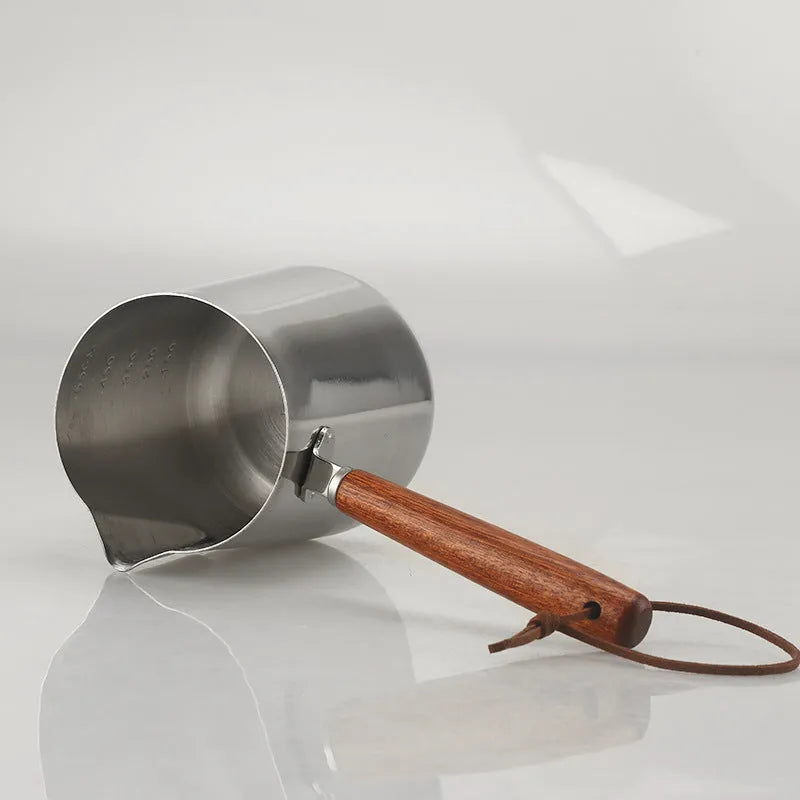 Stainless steel coffee cup with wooden handle showing interior measurement scale markings