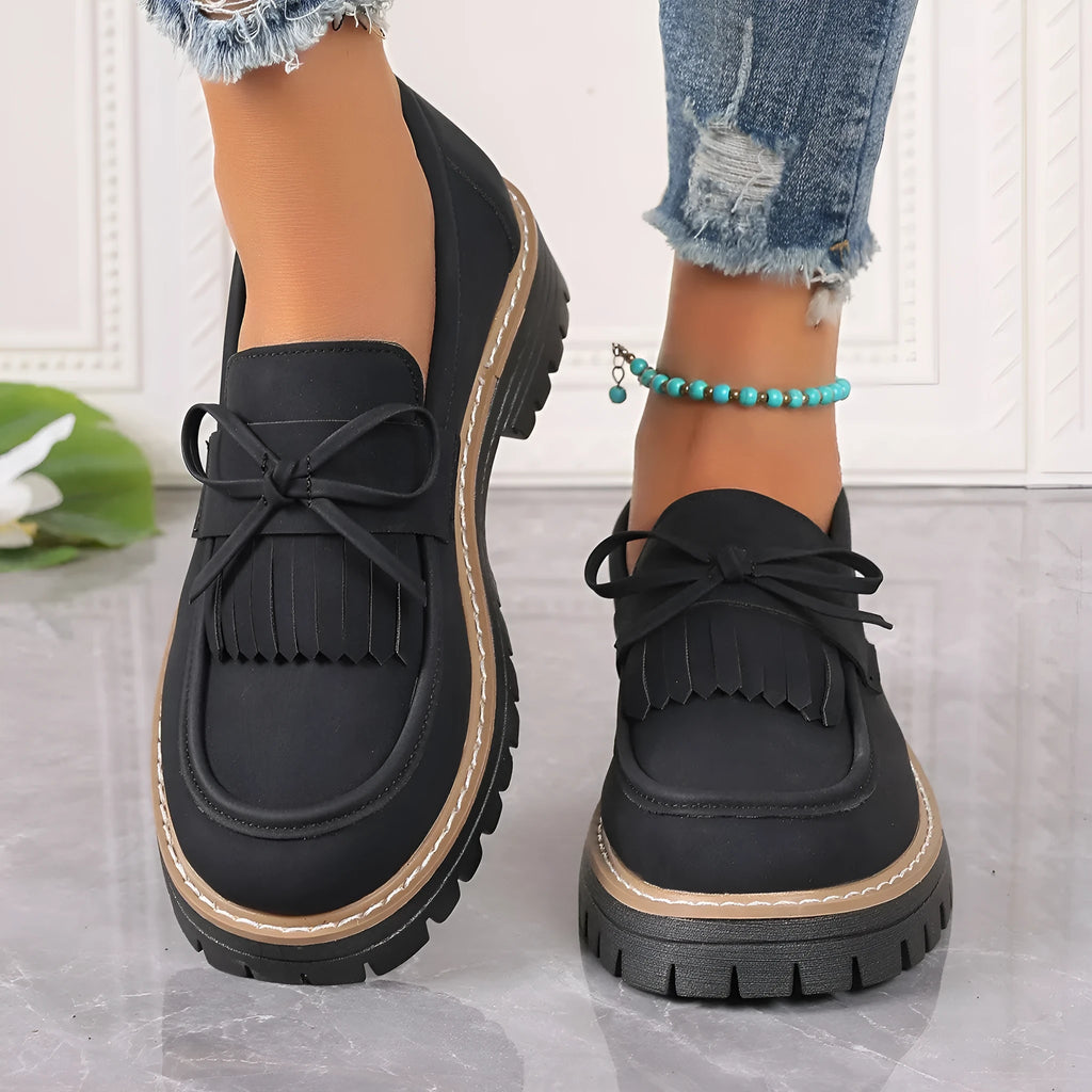 Women's black plus size loafer with tassel and bow decoration on a chunky rubber sole