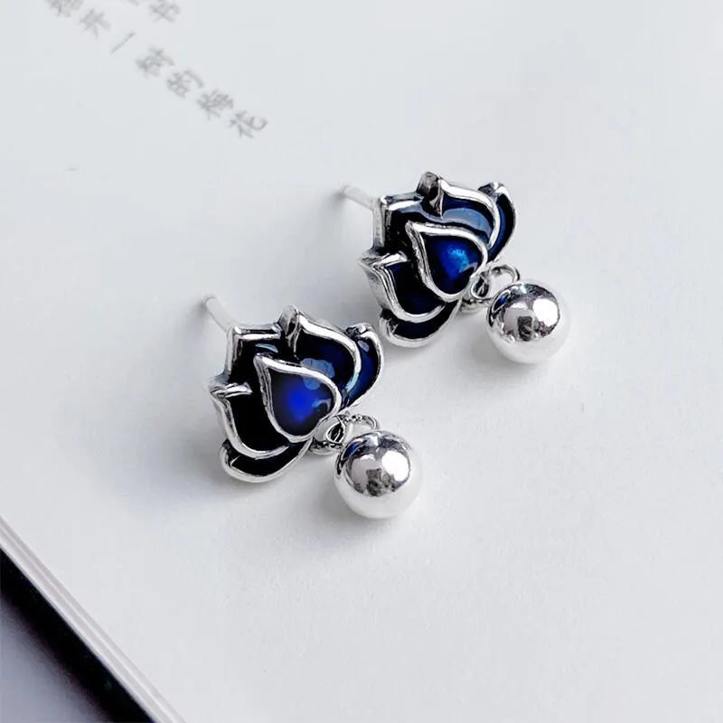 Silver-toned alloy lotus flower earrings with seedpod centre and dangling tassels on a white background.