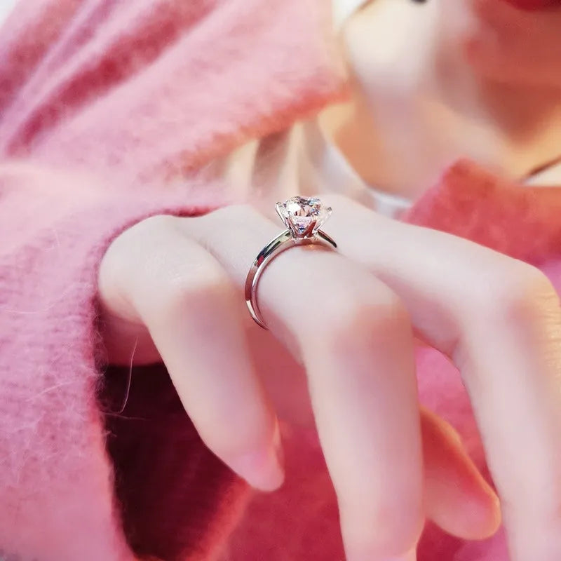 White gold plated ring with six-claw setting holding a central zircon stone on a geometric band.