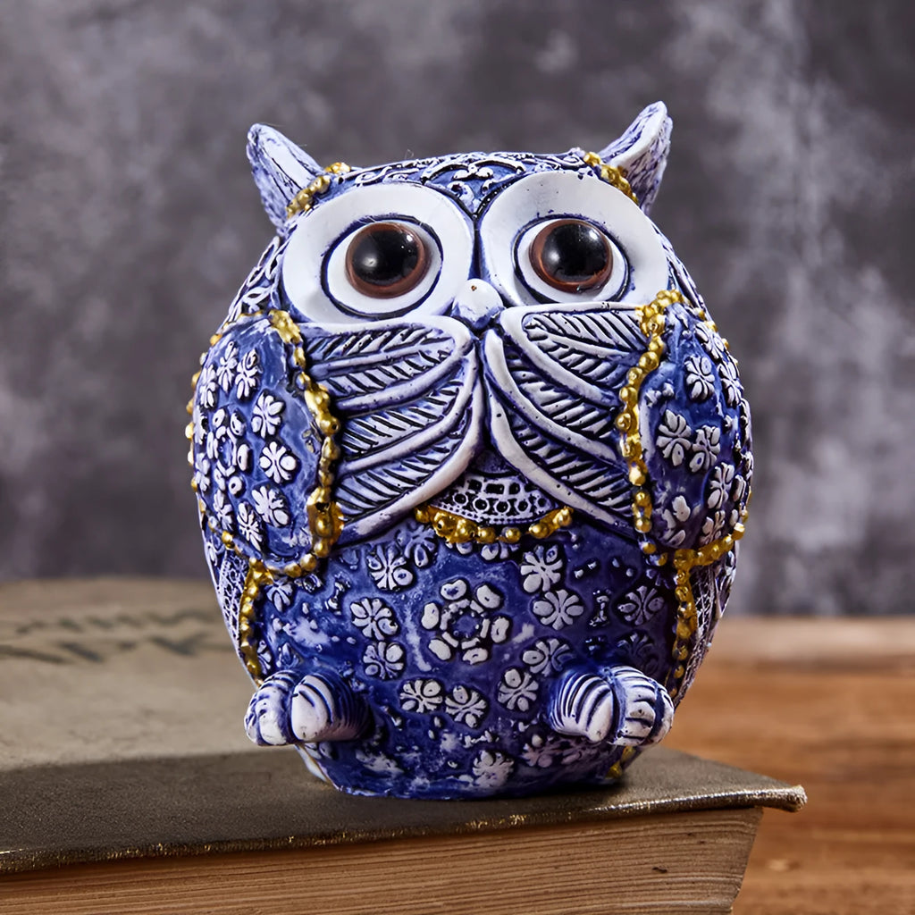 Three blue and white owl resin ornaments in large and small sizes on a white shelf