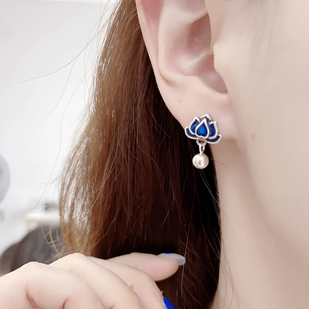Silver-toned alloy lotus flower earrings with seedpod centre and dangling tassels on a white background.