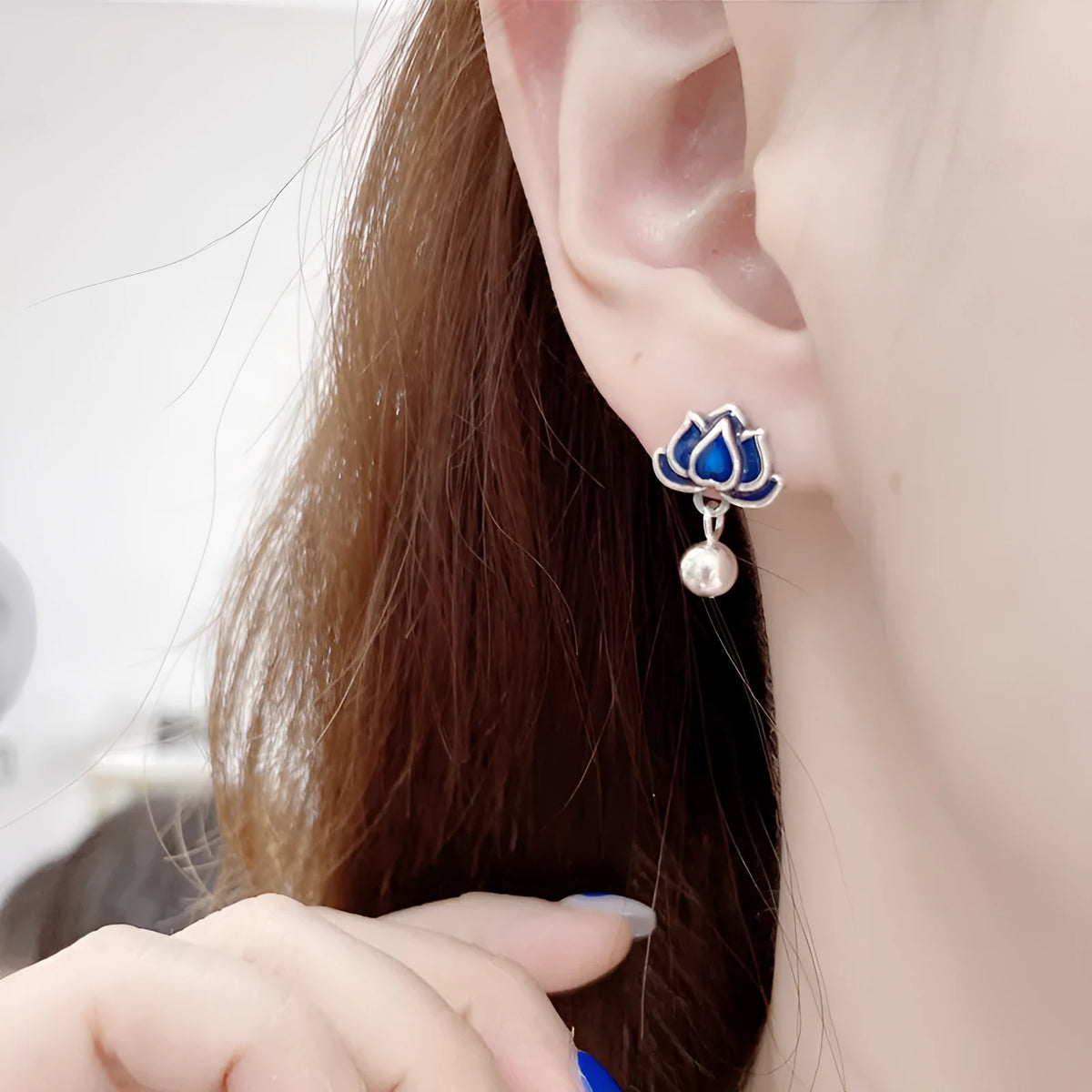 Silver-toned alloy lotus flower earrings with seedpod centre and dangling tassels on a white background.