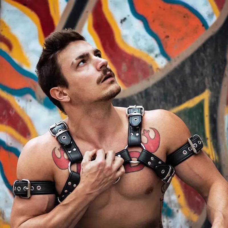 Black leather men's chest bondage strap with a large metal adjustment buckle.