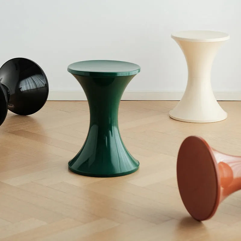 Plastic hourglass style shoe changing stool in green, shown in a home setting.