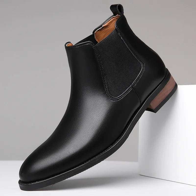 Men's black Chelsea high-top boots with a pointed toe and low rubber sole on a white background.