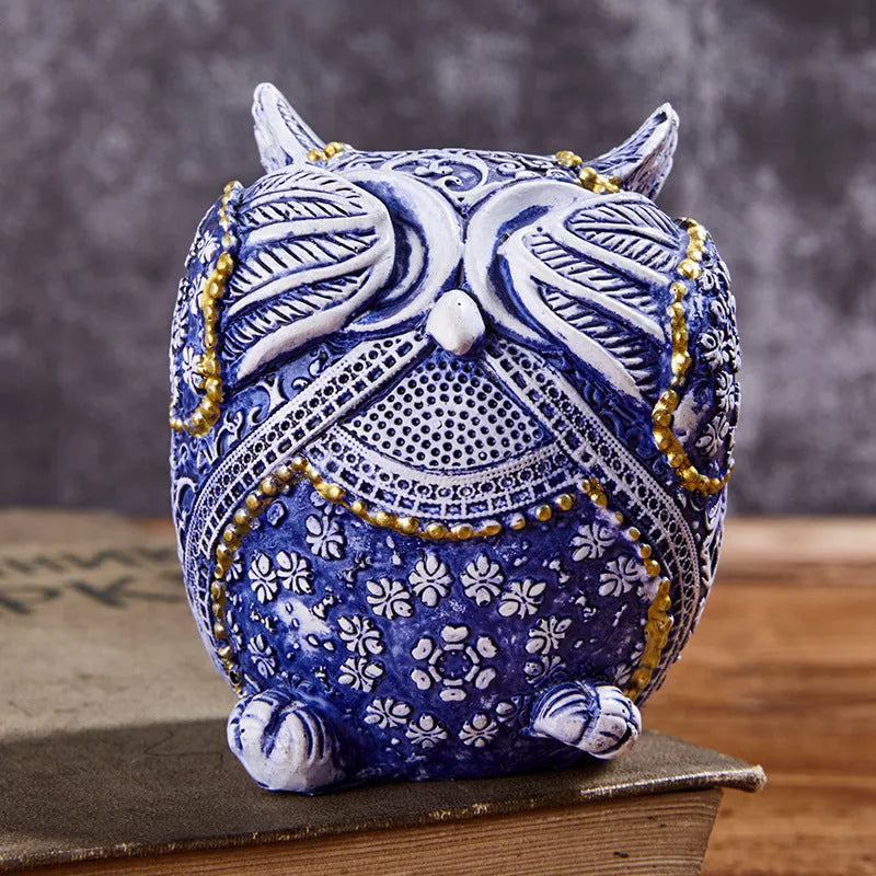 Three blue and white owl resin ornaments in large and small sizes on a white shelf