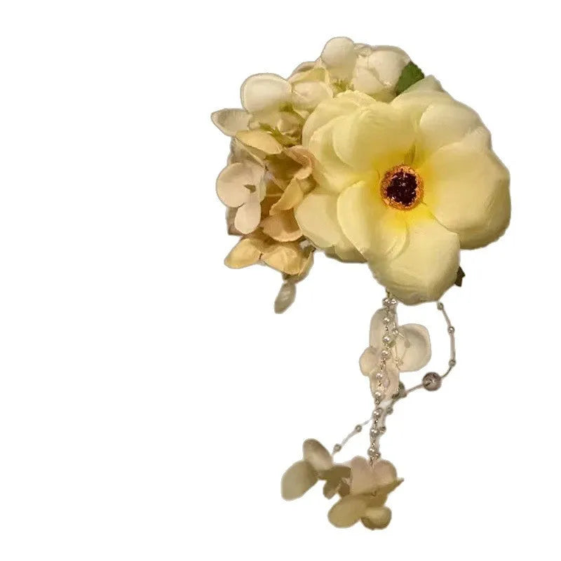 Decorative hair clip with pearls and a long yellow flower tassel on a white background.