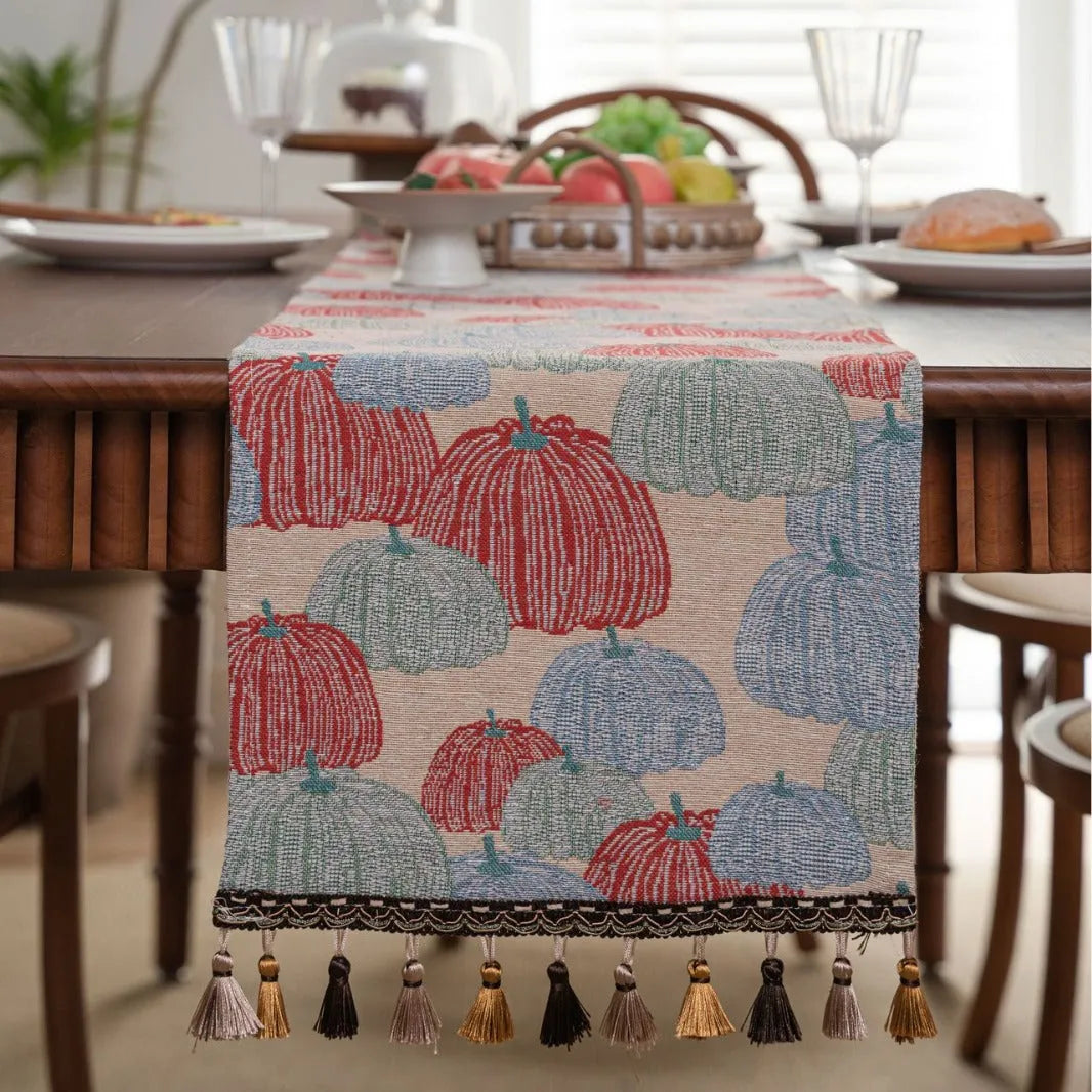 Beige Jacquard table runner with floral leaf pattern and long tassel fringe on a wooden table.