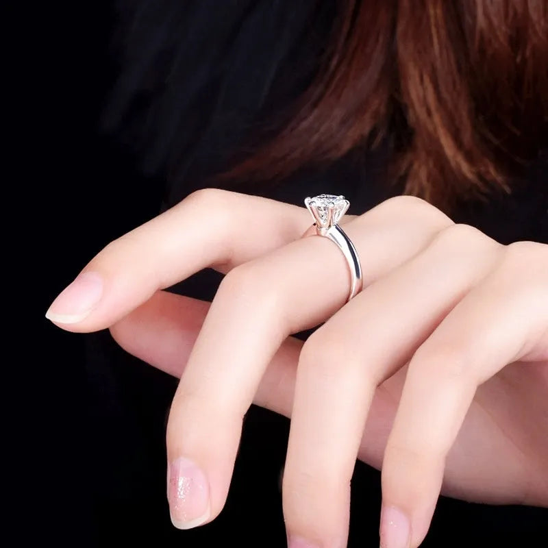 White gold plated ring with six-claw setting holding a central zircon stone on a geometric band.