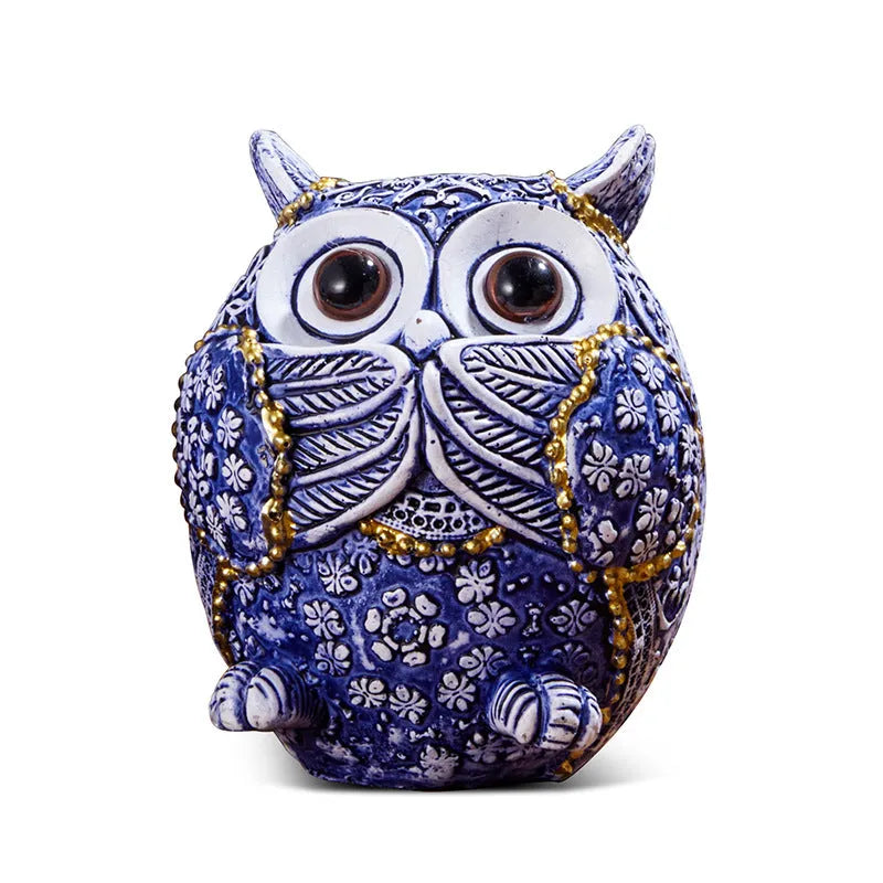 Three blue and white owl resin ornaments in large and small sizes on a white shelf