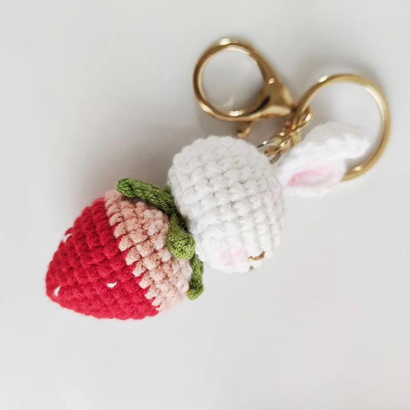 Hand-woven white rabbit strawberry pendant with keychain on grey background