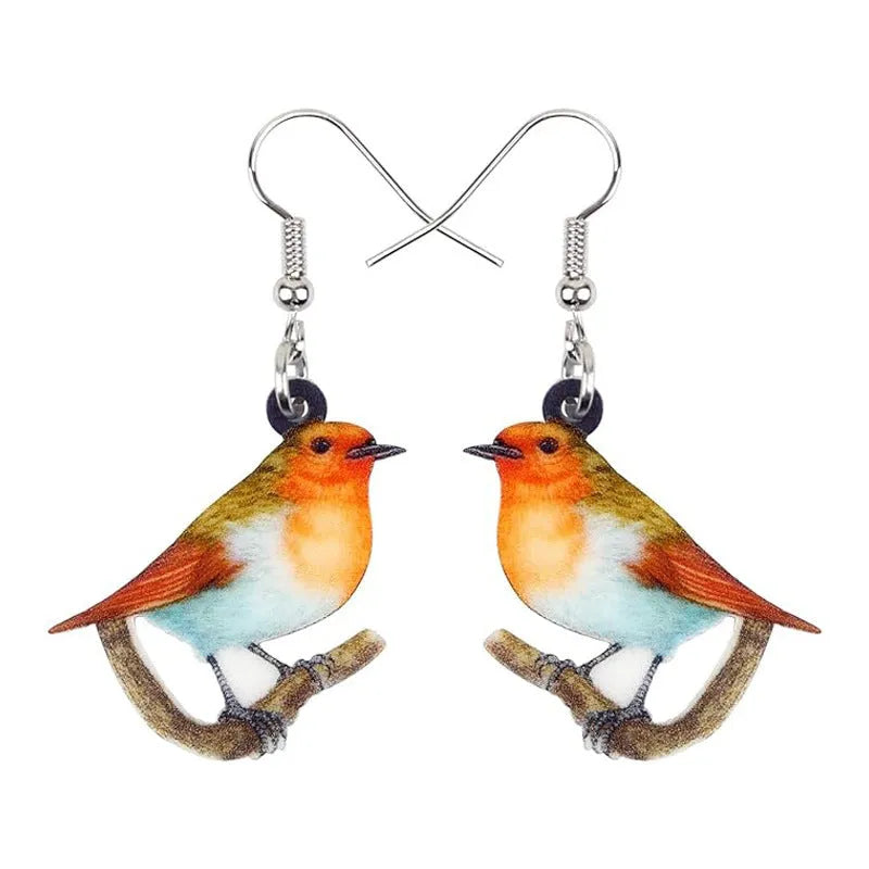A pair of blue titmouse bird pendant earrings made from clear acrylic with geometric shapes and snake chain links.