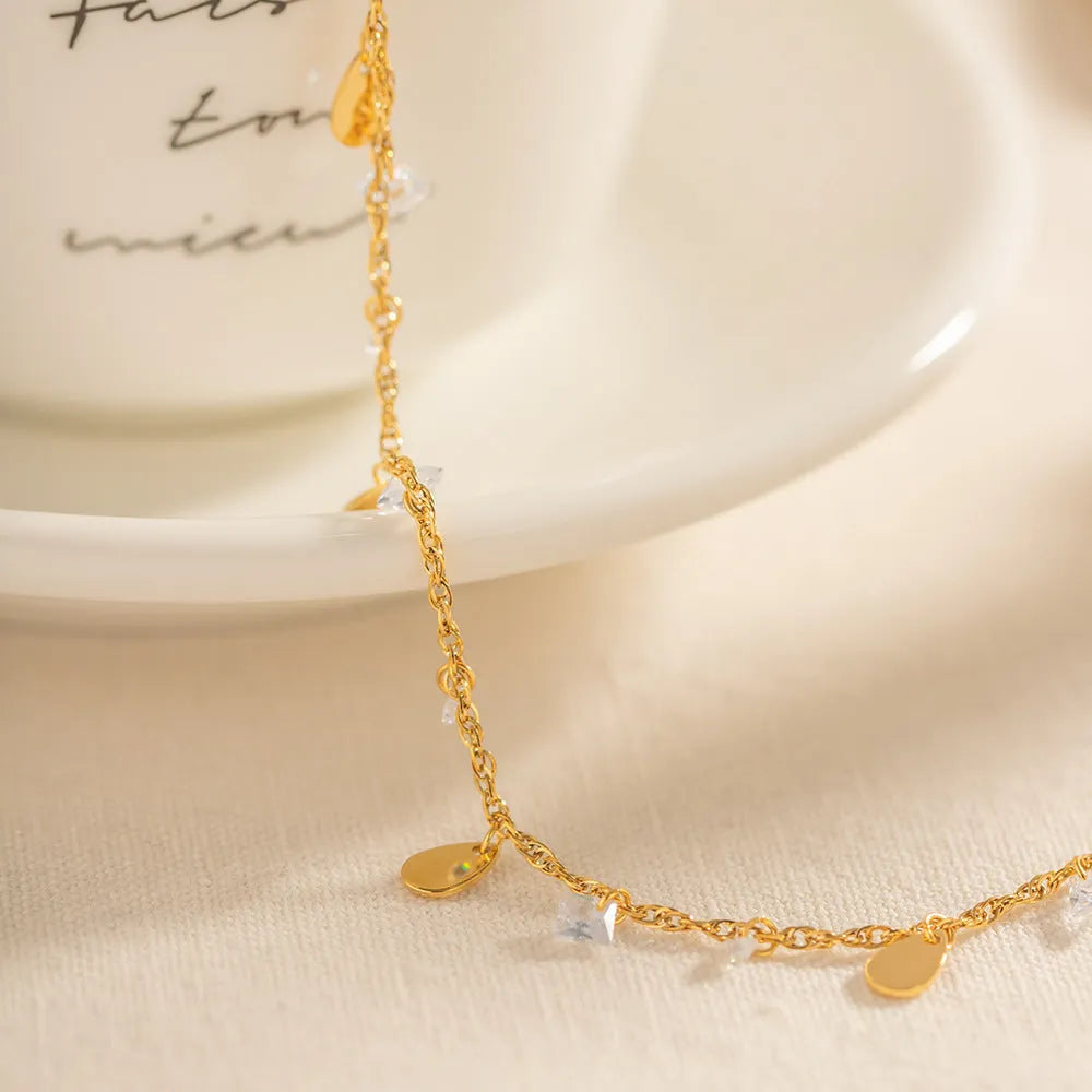 Women's stainless steel anklet with a silver water drop tassel charm and geometric links on an adjustable chain.