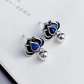 Silver-toned alloy lotus flower earrings with seedpod centre and dangling tassels on a white background.