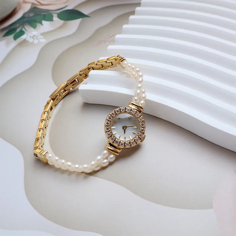 Women's light gold bracelet watch with freshwater pearls on stainless steel strap and 18mm dial.