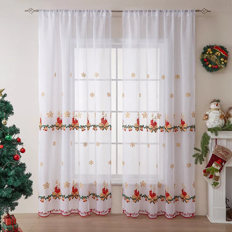 Pair of white Christmas curtains with red and green embroidered snowflakes, shown hanging in a window.
