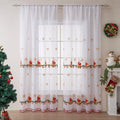 Pair of white Christmas curtains with red and green embroidered snowflakes, shown hanging in a window.