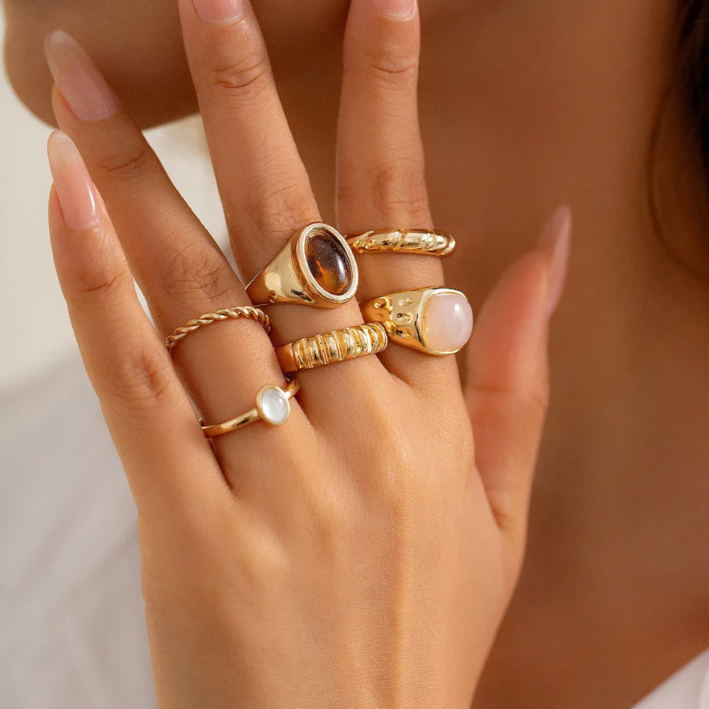 Set of six light gold alloy rings with irregular geometric shapes and rounded elements