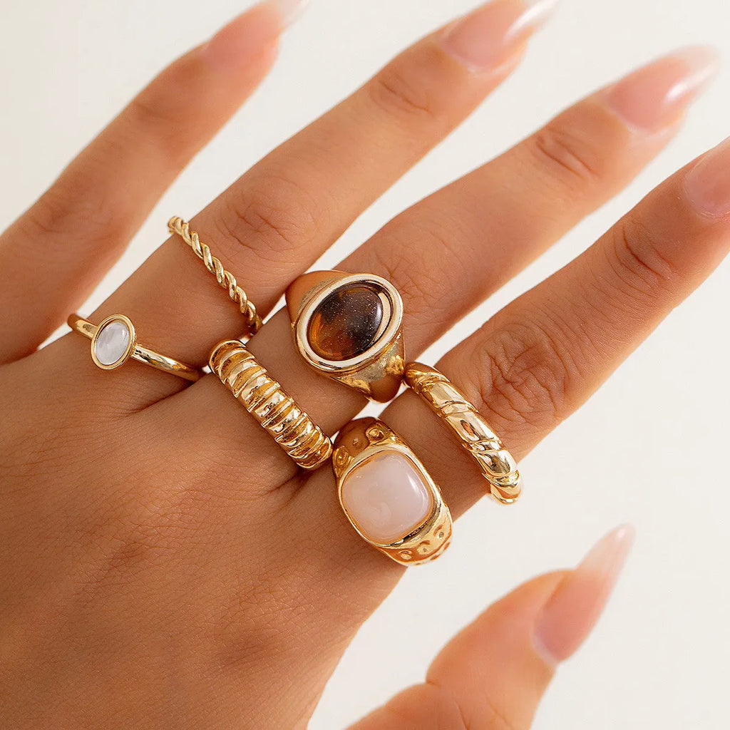Set of six light gold alloy rings with irregular geometric shapes and rounded elements