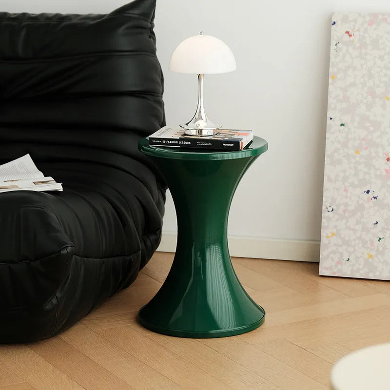 Plastic hourglass style shoe changing stool in green, shown in a home setting.