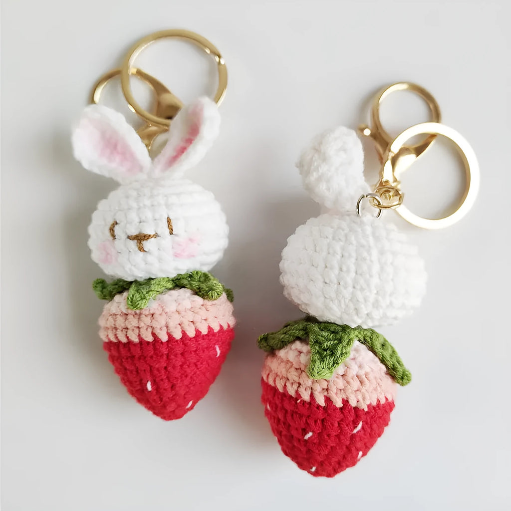 Hand-woven white rabbit strawberry pendant with keychain on grey background