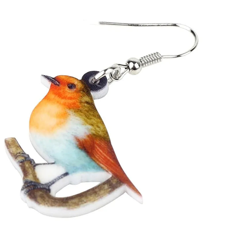 A pair of blue titmouse bird pendant earrings made from clear acrylic with geometric shapes and snake chain links.