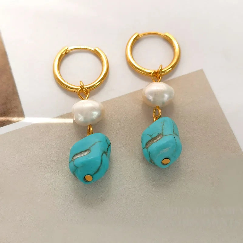 A pair of geometric turquoise and cultured pearl ear clips on a copper setting.