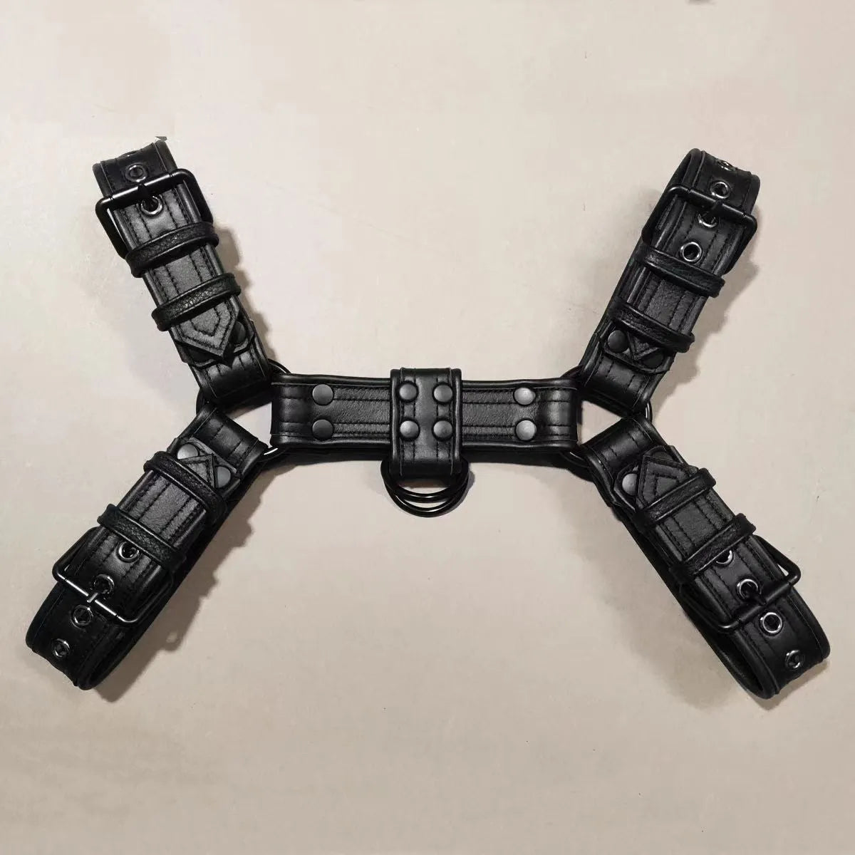 Black leather men's chest bondage strap with a large metal adjustment buckle.