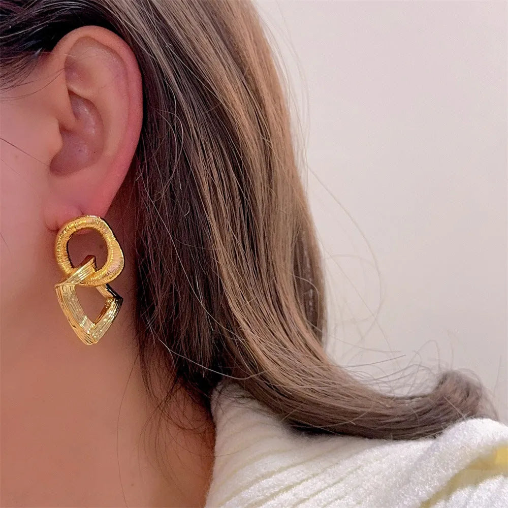 A pair of retro-style geometric circle drop earrings in a gold tone with a 3.4cm pendant length.