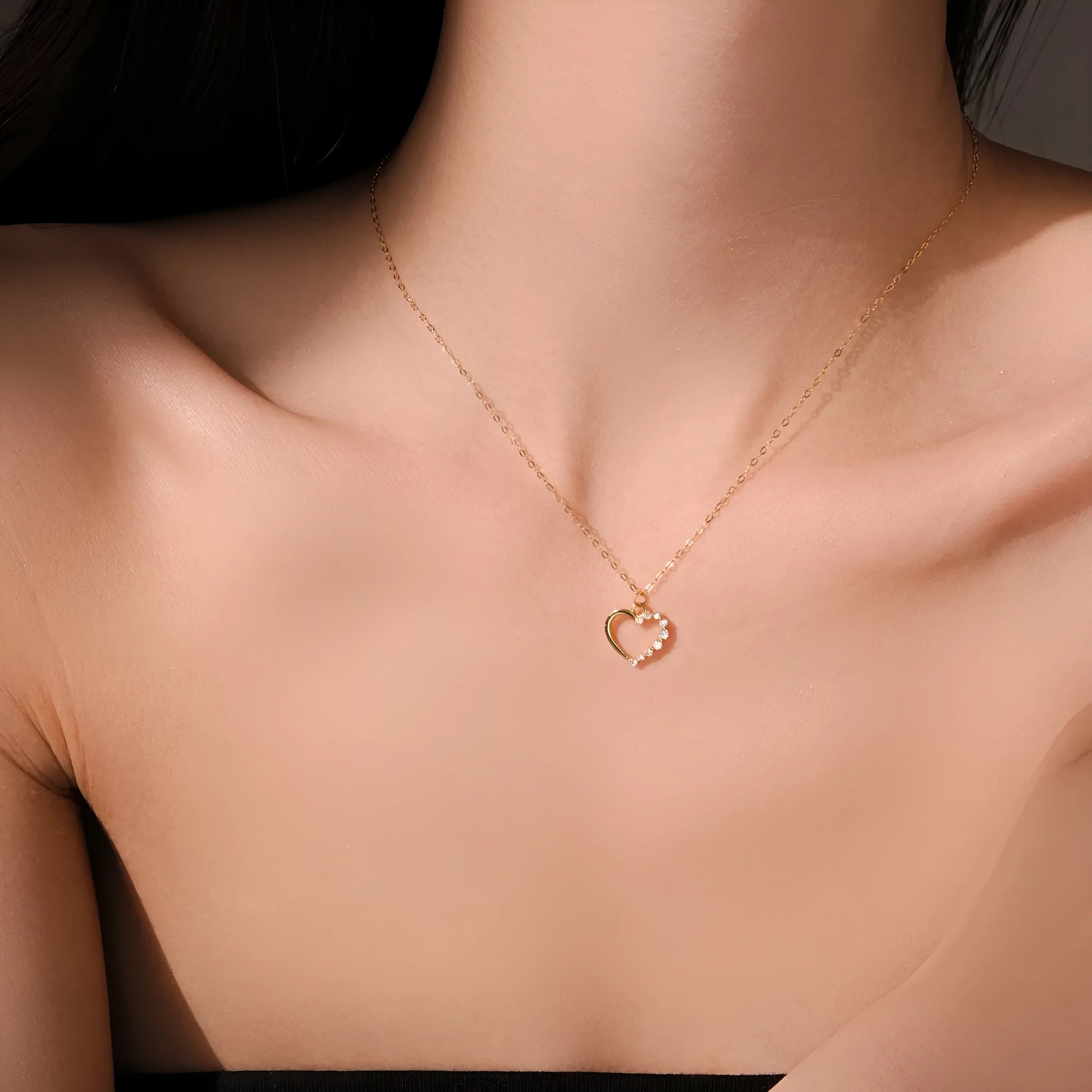 Close-up of a hollow heart-shaped sterling silver pendant on an oval chain, shown in both gold and white gold plated finishes.
