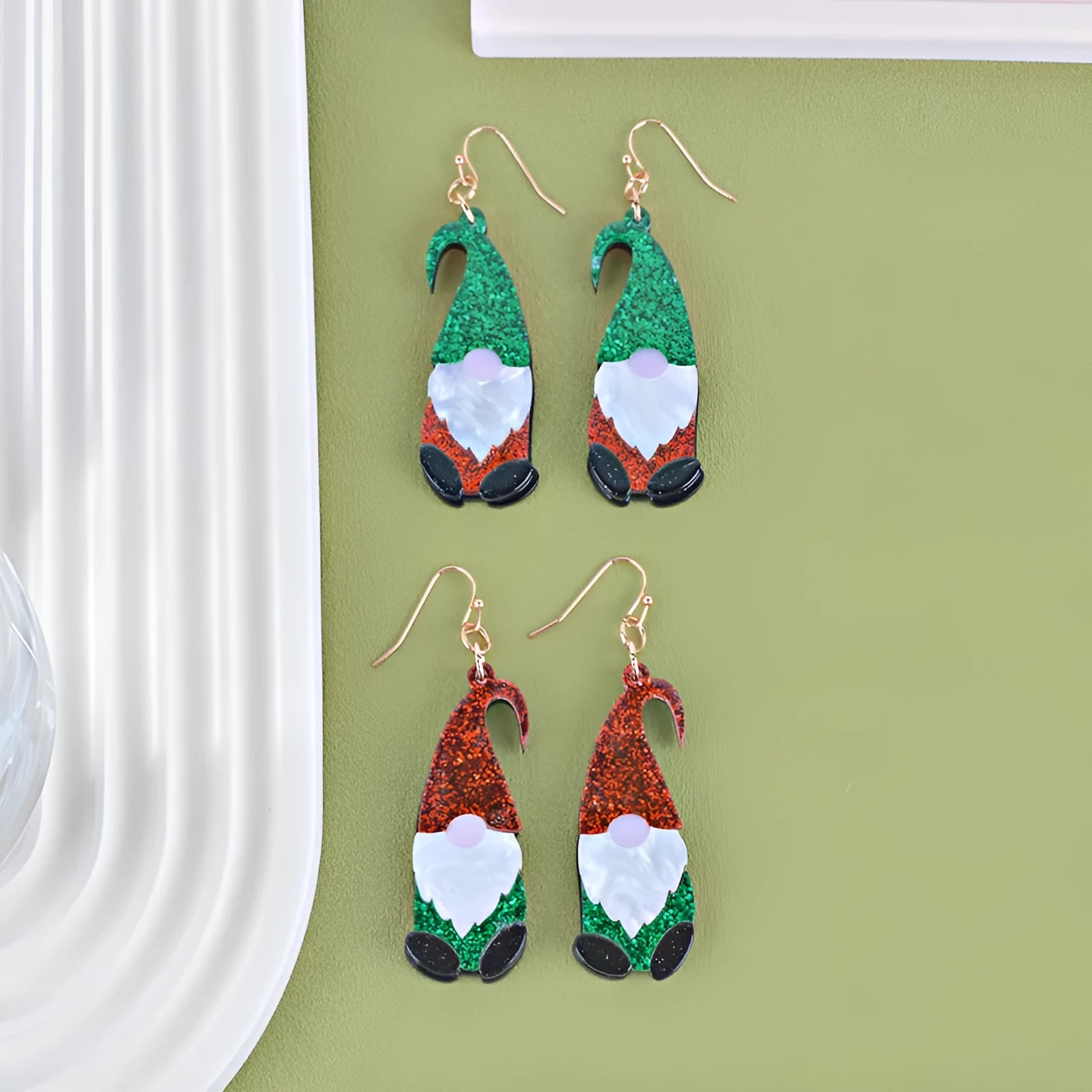 A pair of cartoon Santa Claus acrylic fashion earrings on a red background.