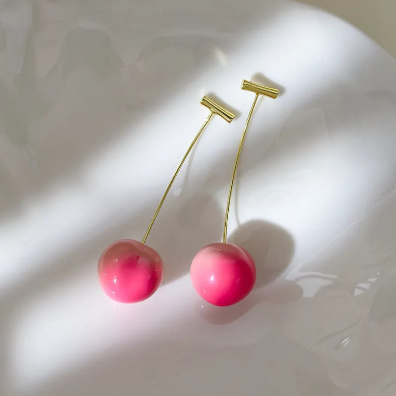 A pair of acrylic peach-shaped earrings on copper findings, shown in small and large size options.