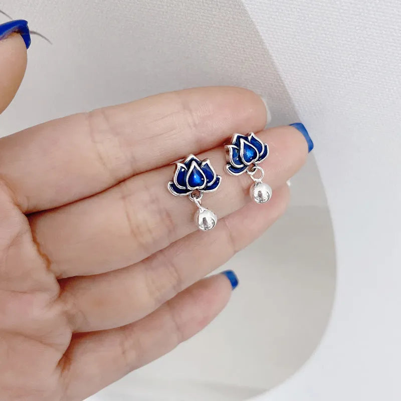 Silver-toned alloy lotus flower earrings with seedpod centre and dangling tassels on a white background.