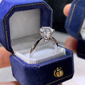 White gold plated ring with six-claw setting holding a central zircon stone on a geometric band.