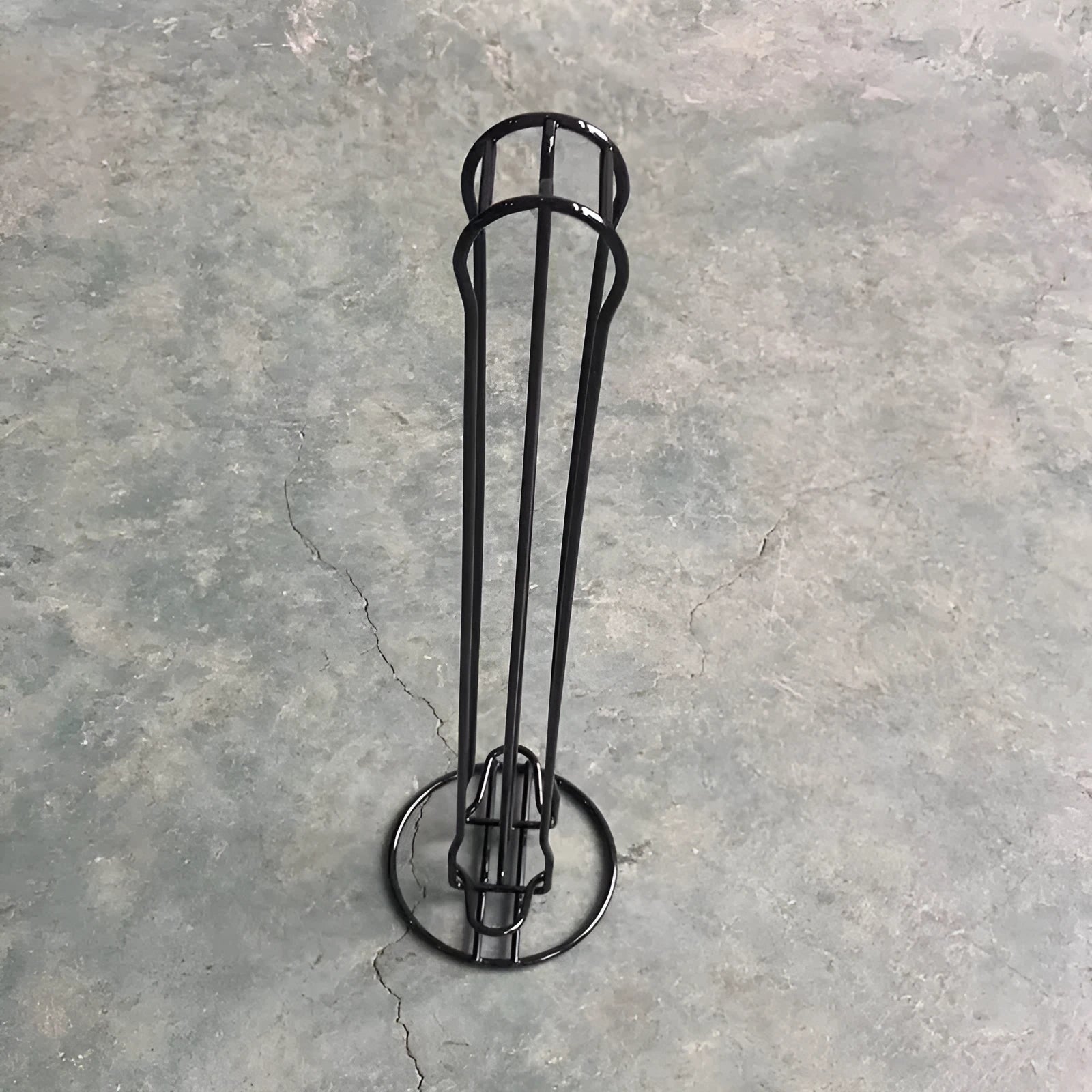 Black wrought iron coffee capsule storage rack holding 20 single-serve pods on display shelves.