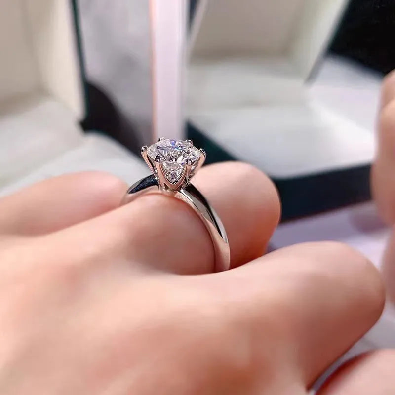 White gold plated ring with six-claw setting holding a central zircon stone on a geometric band.