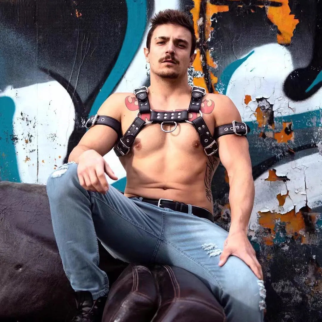 Black leather men's chest bondage strap with a large metal adjustment buckle.