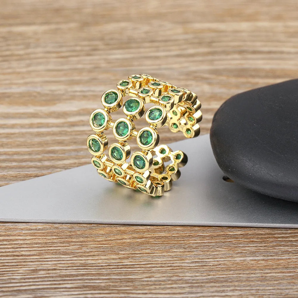 Copper ring with 18K gold plating, green zircon stones, and exaggerated three-layer wide band design.
